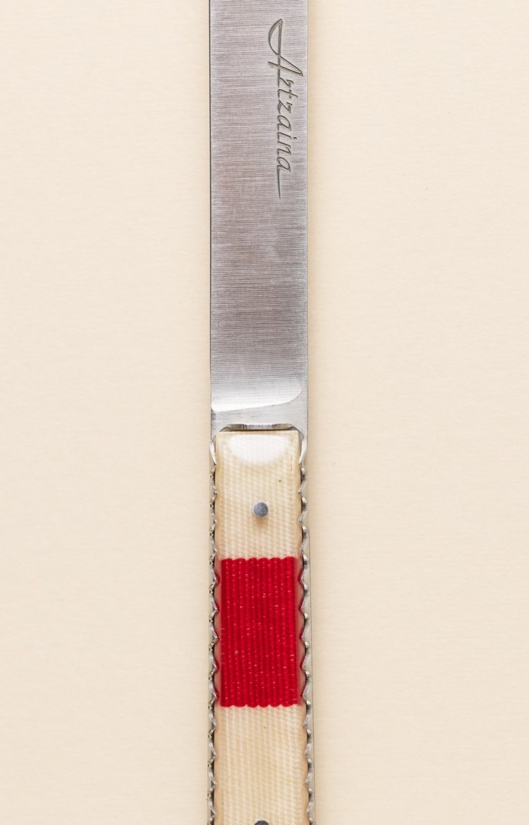 Photo de Artzaina, couteau artisanal en linge basque rouge avec trois bandes blanches, plan rapproché