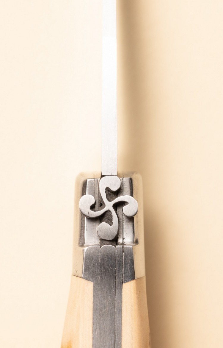 Photo de la croix basque sculptée à la main sur le ressort du couteau artisanal basque Mizpira en néflier